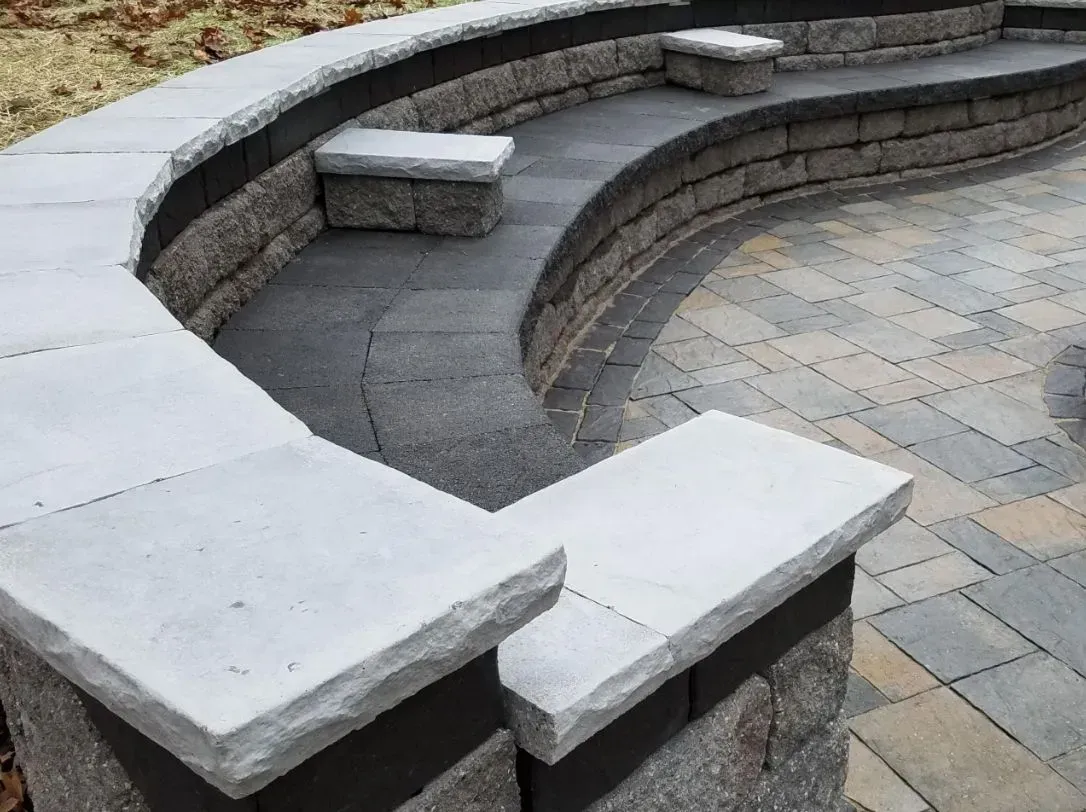 Curved stone amphitheater seating with gray benches and tiled floor outdoors