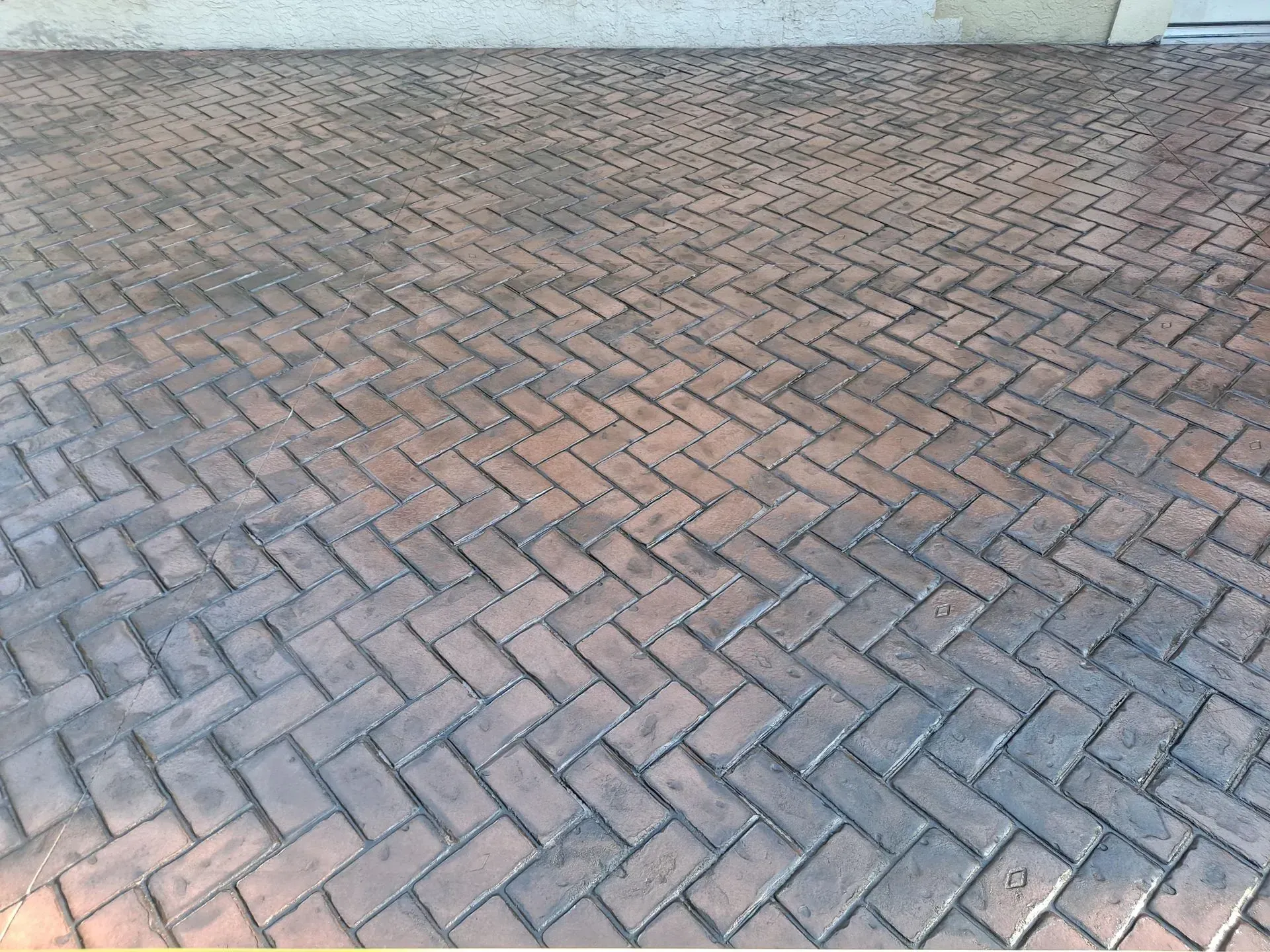 Brick-paved ground with a herringbone pattern and a light wall in the background