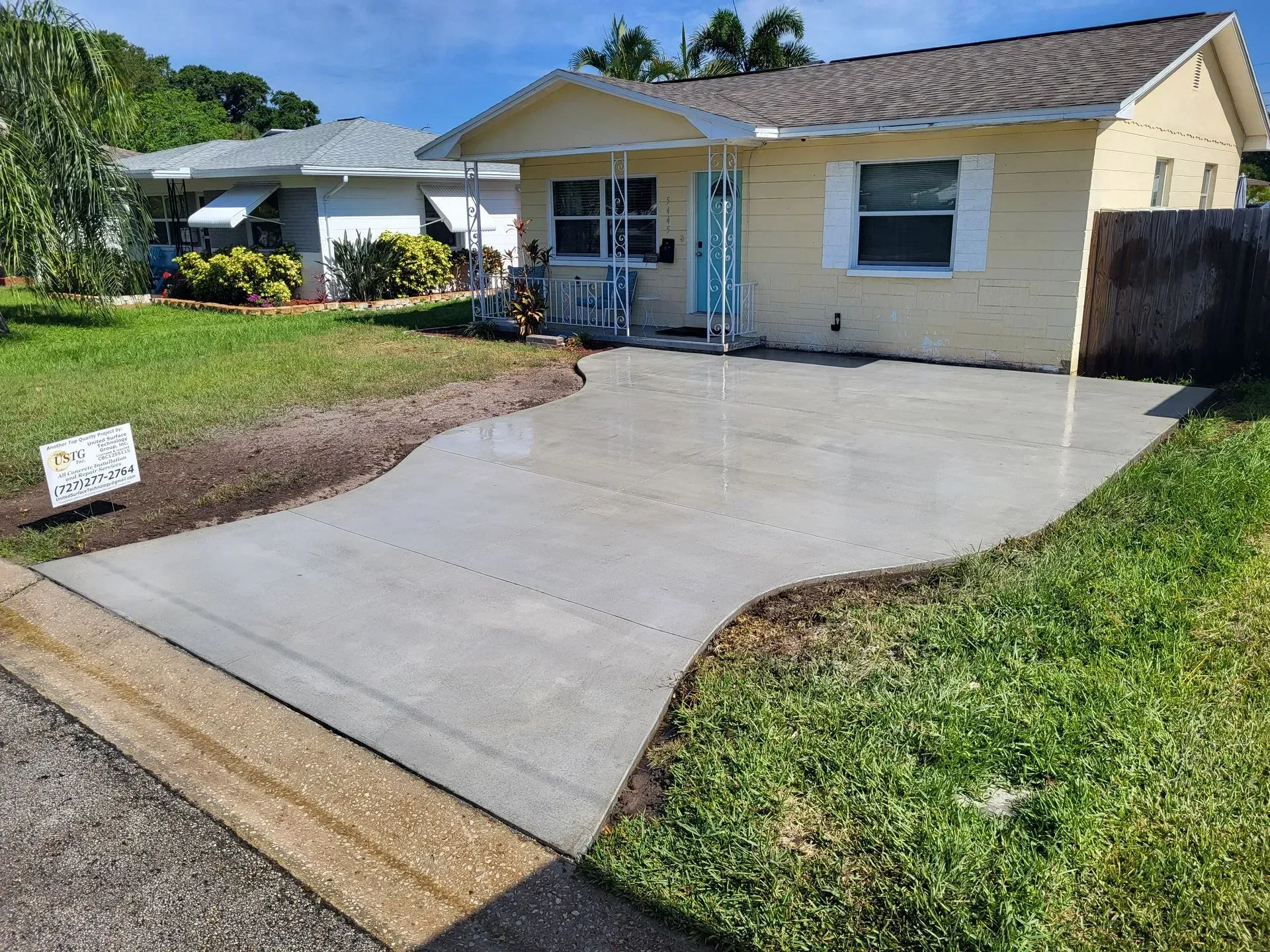 Single-story yellow house with a wide concrete driveway and small front porch.