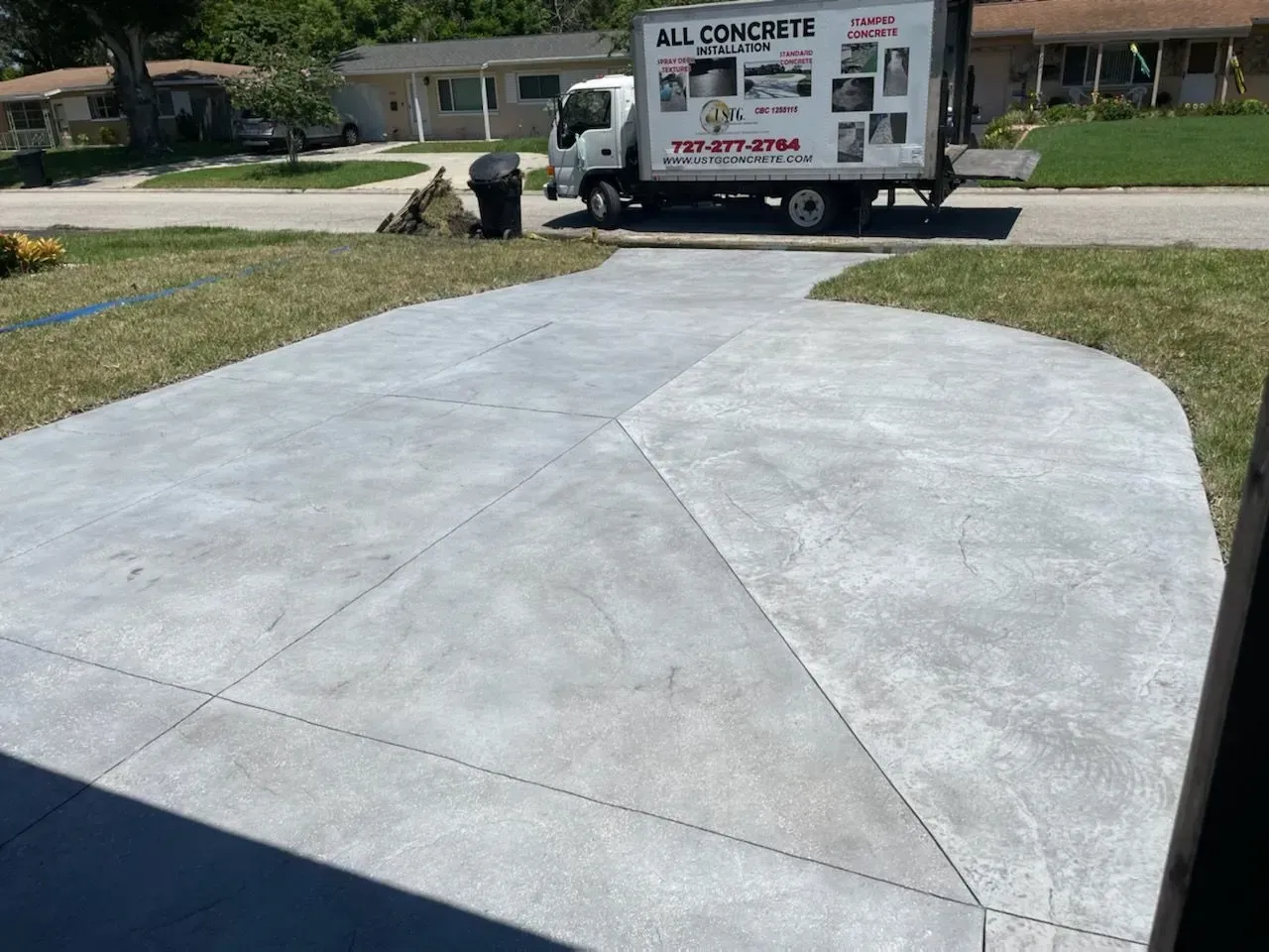 Freshly poured concrete driveway with a concrete truck in a suburban neighborhood