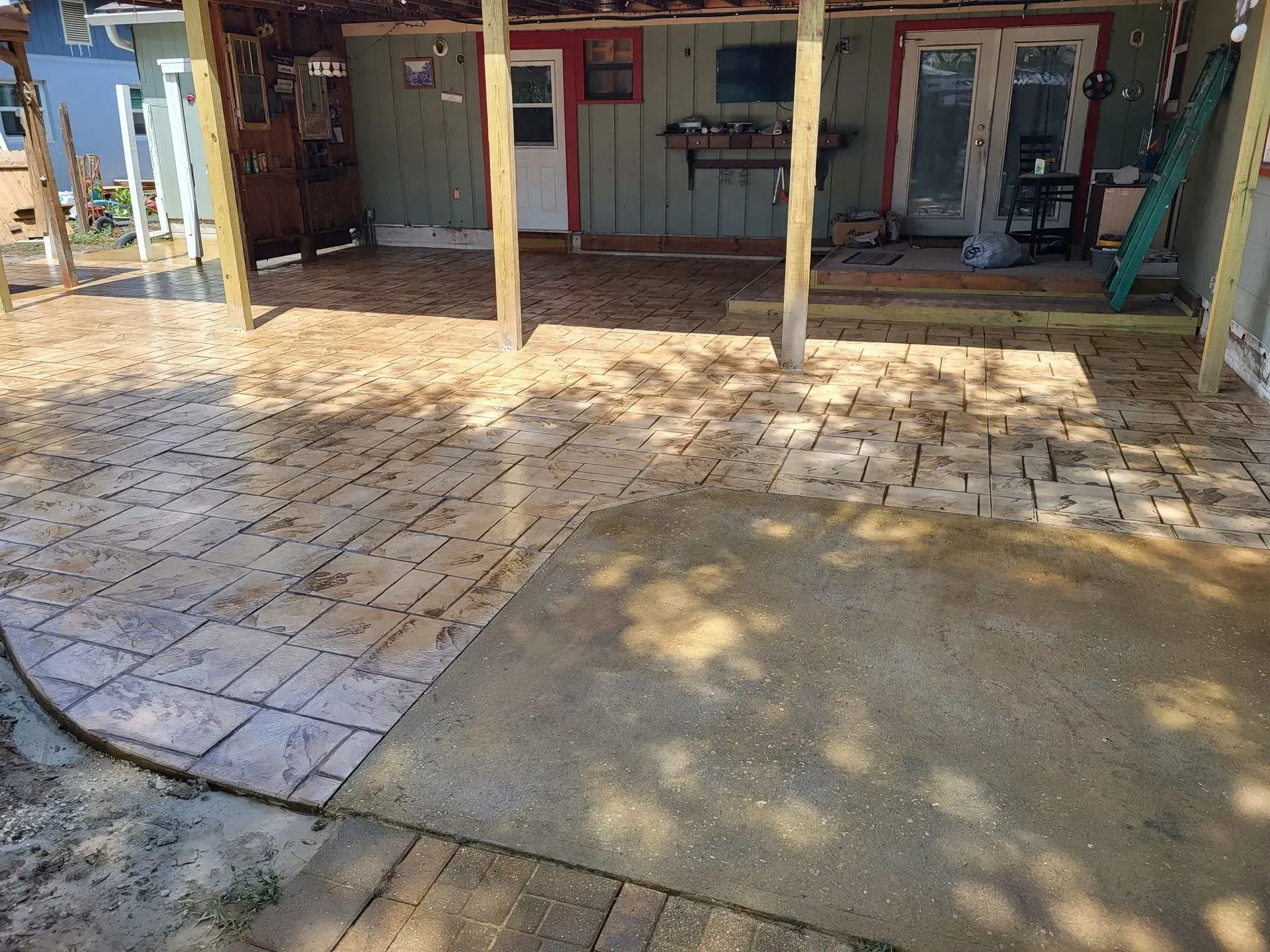 Shaded outdoor patio with tiled and concrete floor in front of a building with open doorways