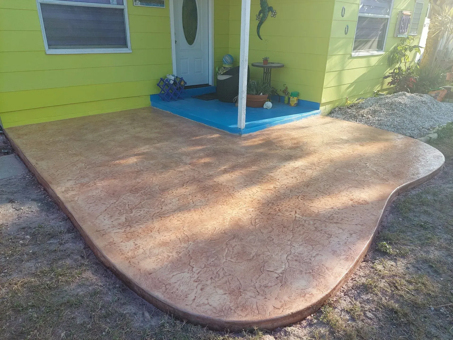 Front porch with lime-green house, blue entry steps, and a large curved concrete patio.