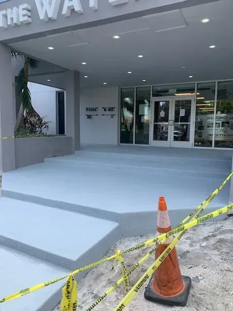 Building entrance under construction with orange cones and yellow caution tape blocking the walkway