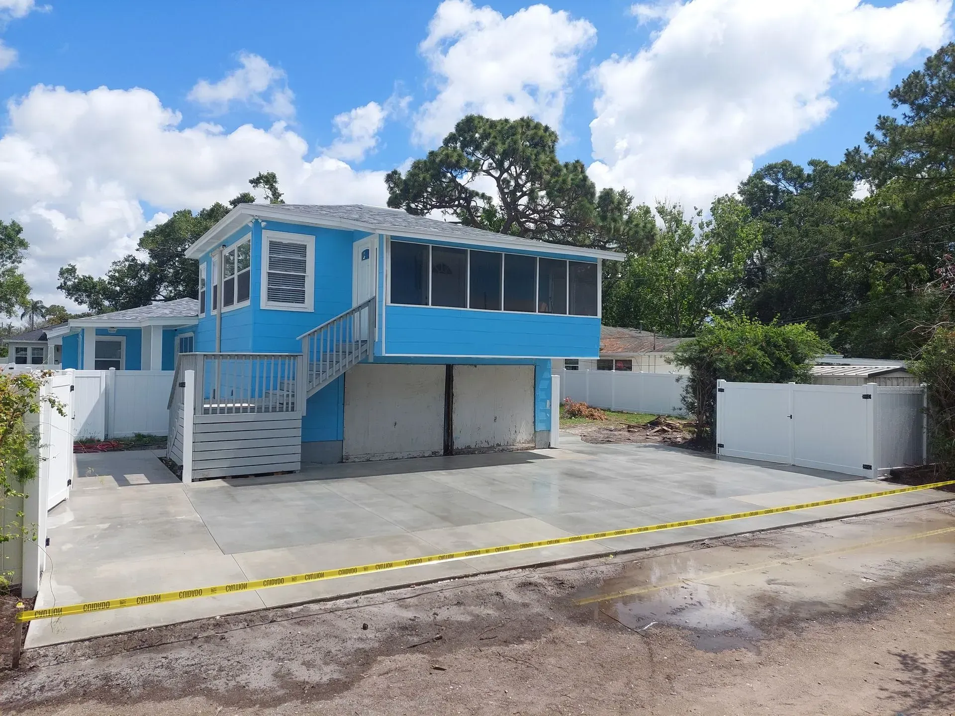Blue elevated building with stairs and white trim in a parking lot under a cloudy sky