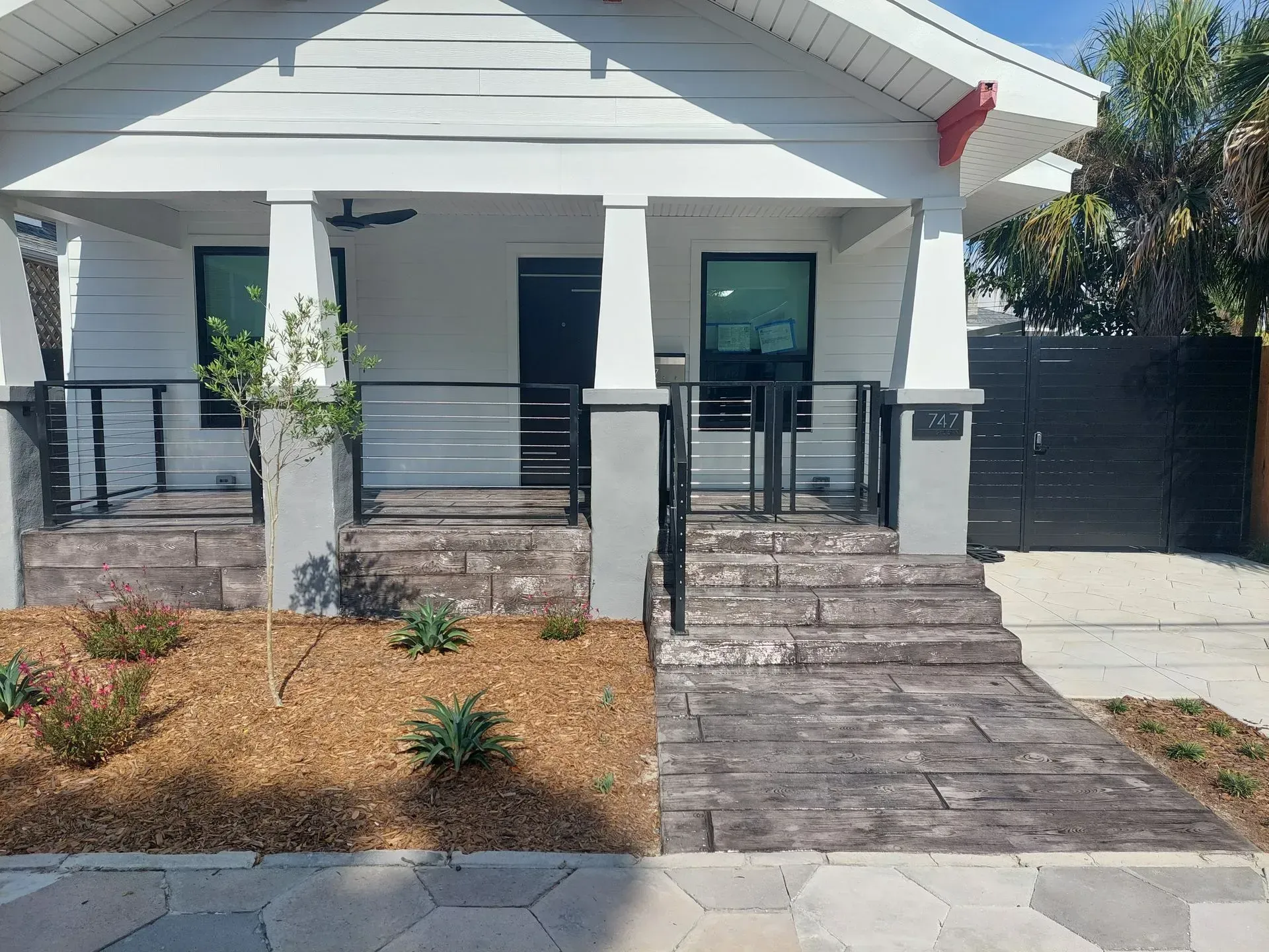 Single-story white house with front porch, ramp, steps, and landscaped yard