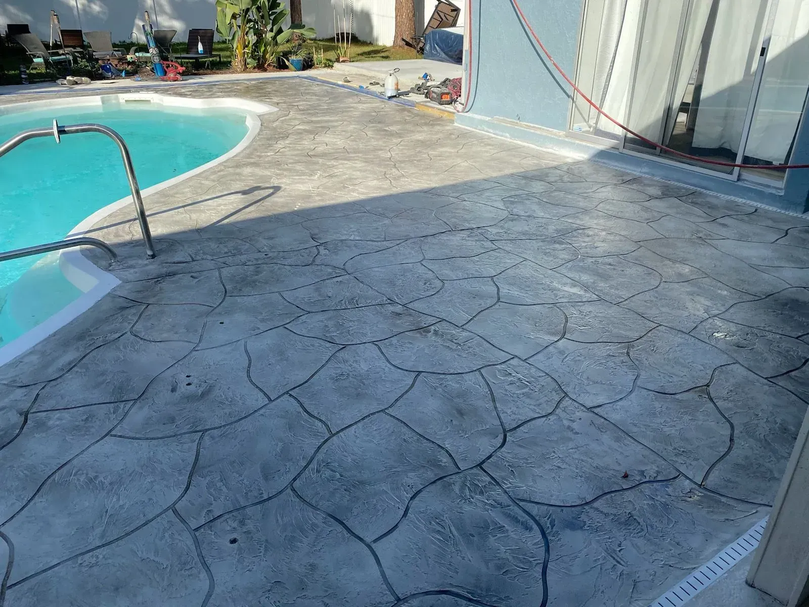 Poolside concrete patio with decorative stamped pattern beside a swimming pool