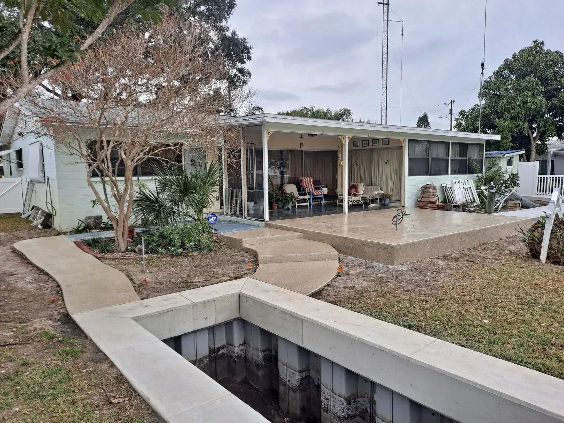Single-story house with a front porch, concrete walkway, and a drainage ditch in the foreground.