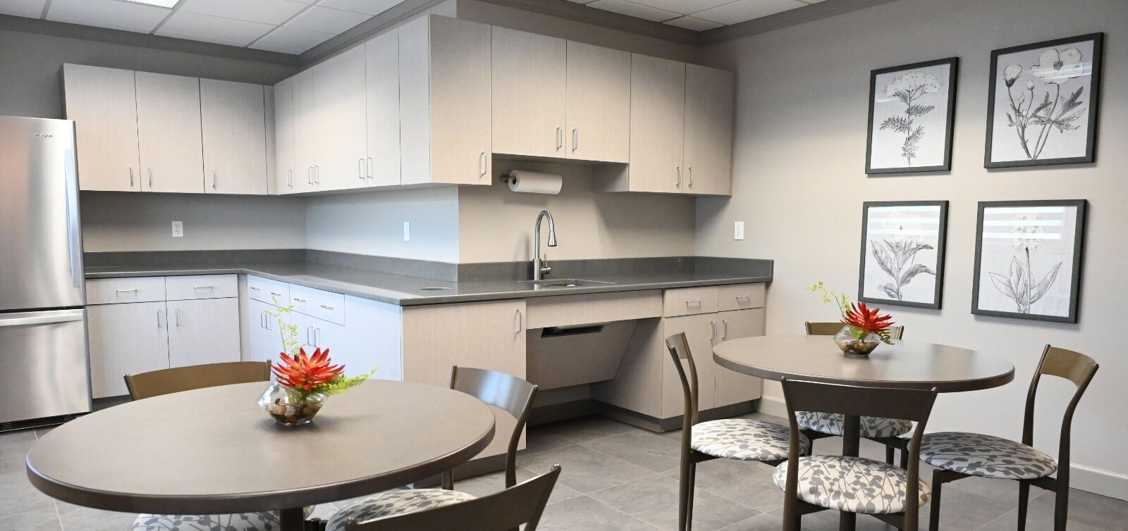A kitchen with tables and chairs and a sink.