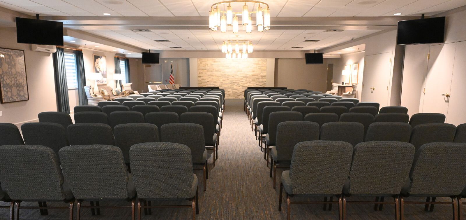 A large auditorium with rows of chairs and a chandelier hanging from the ceiling.