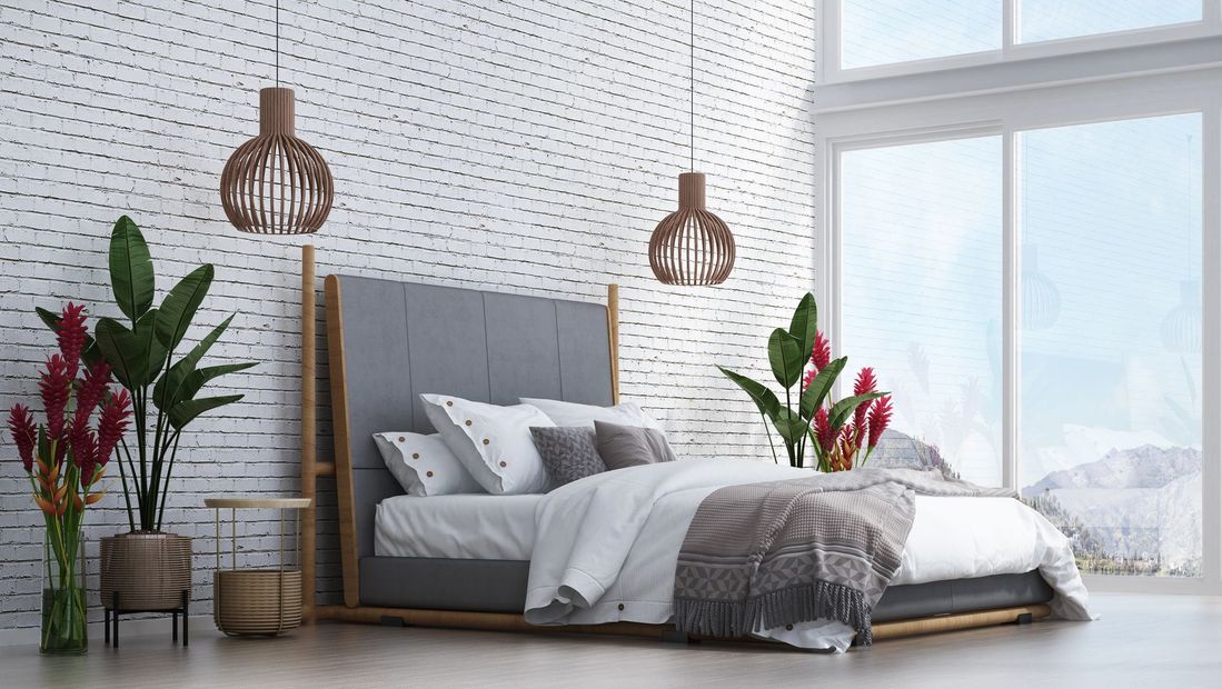 Camera da letto moderna con letto grigio, testiera in legno, tappeto scuro e ampia finestra.