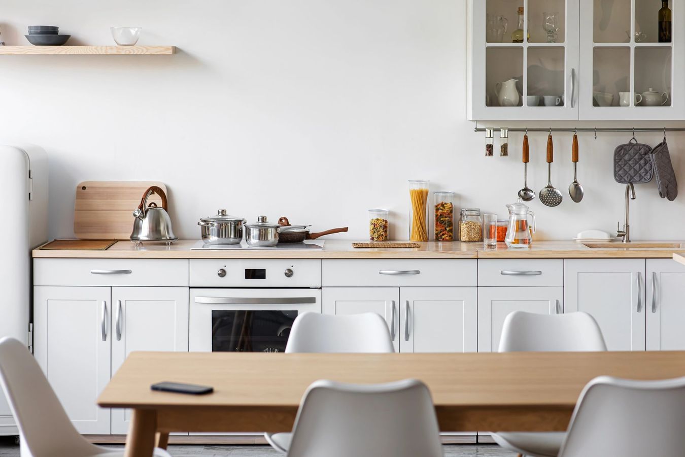 Cucina moderna con mobili grigi, isola, forno incorporato e paraschizzi in marmo.