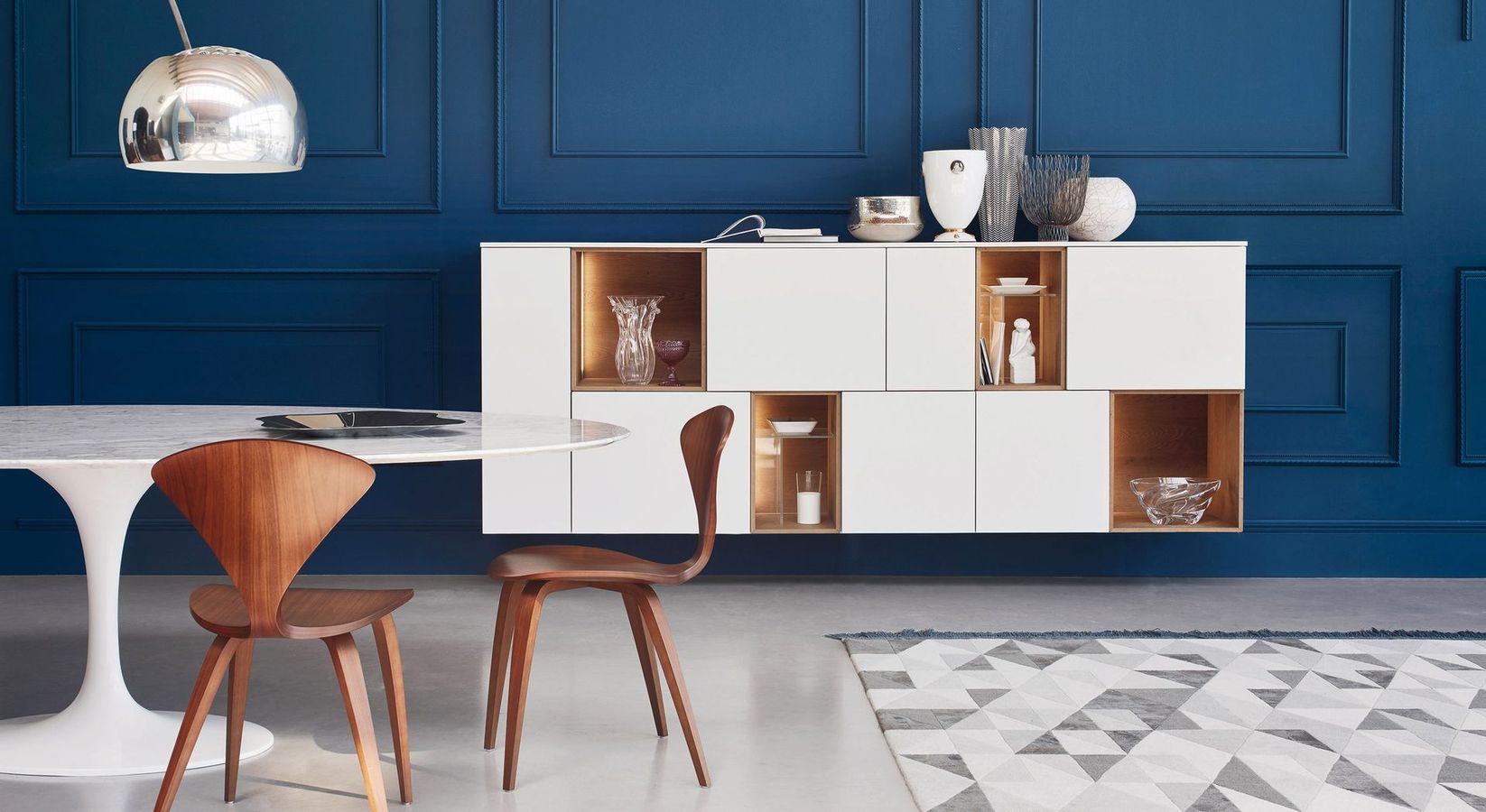 Soggiorno moderno con mobili grigio chiaro, colori neutri e decorazioni geometriche alle pareti.
