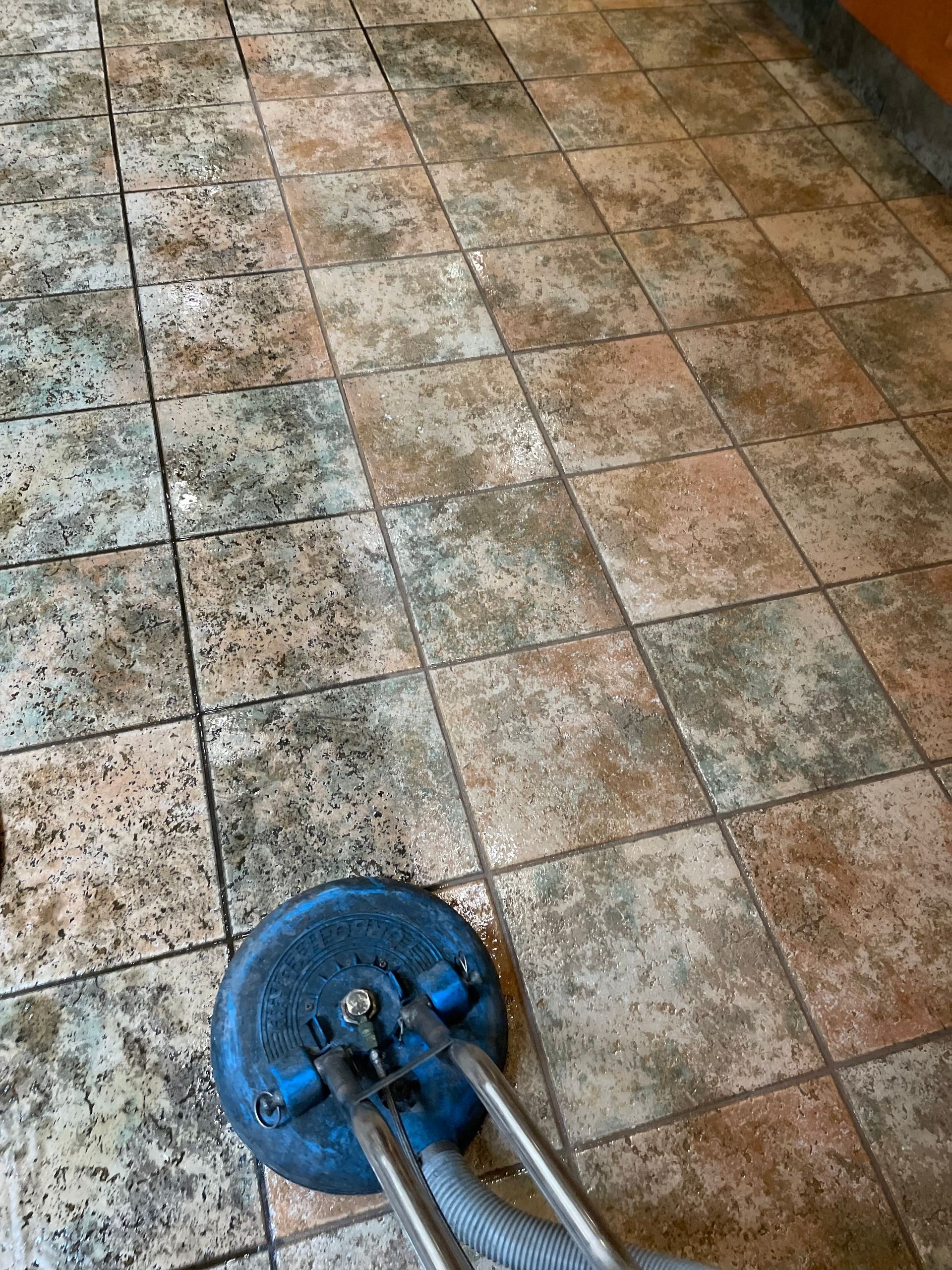 A tile floor is being cleaned with a vacuum cleaner.