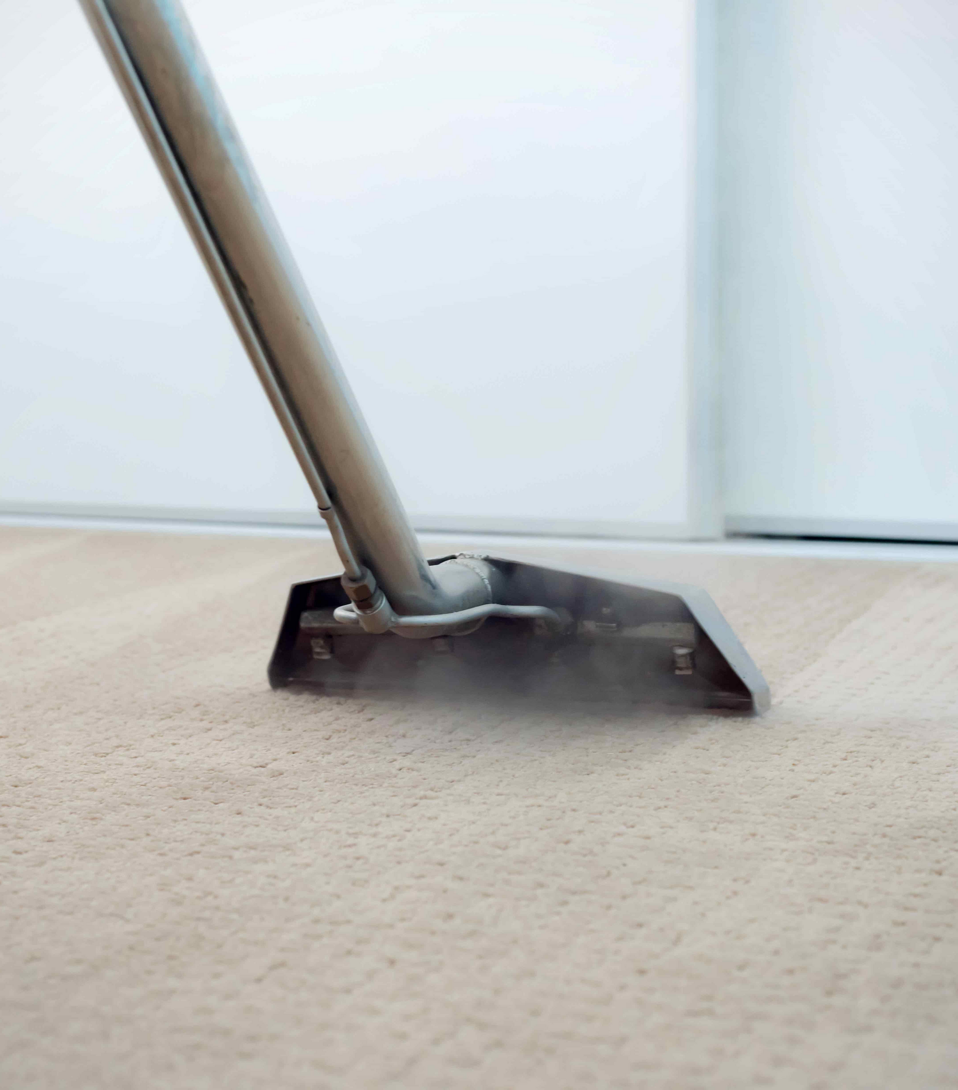 A vacuum cleaner is cleaning a carpet in a room.
