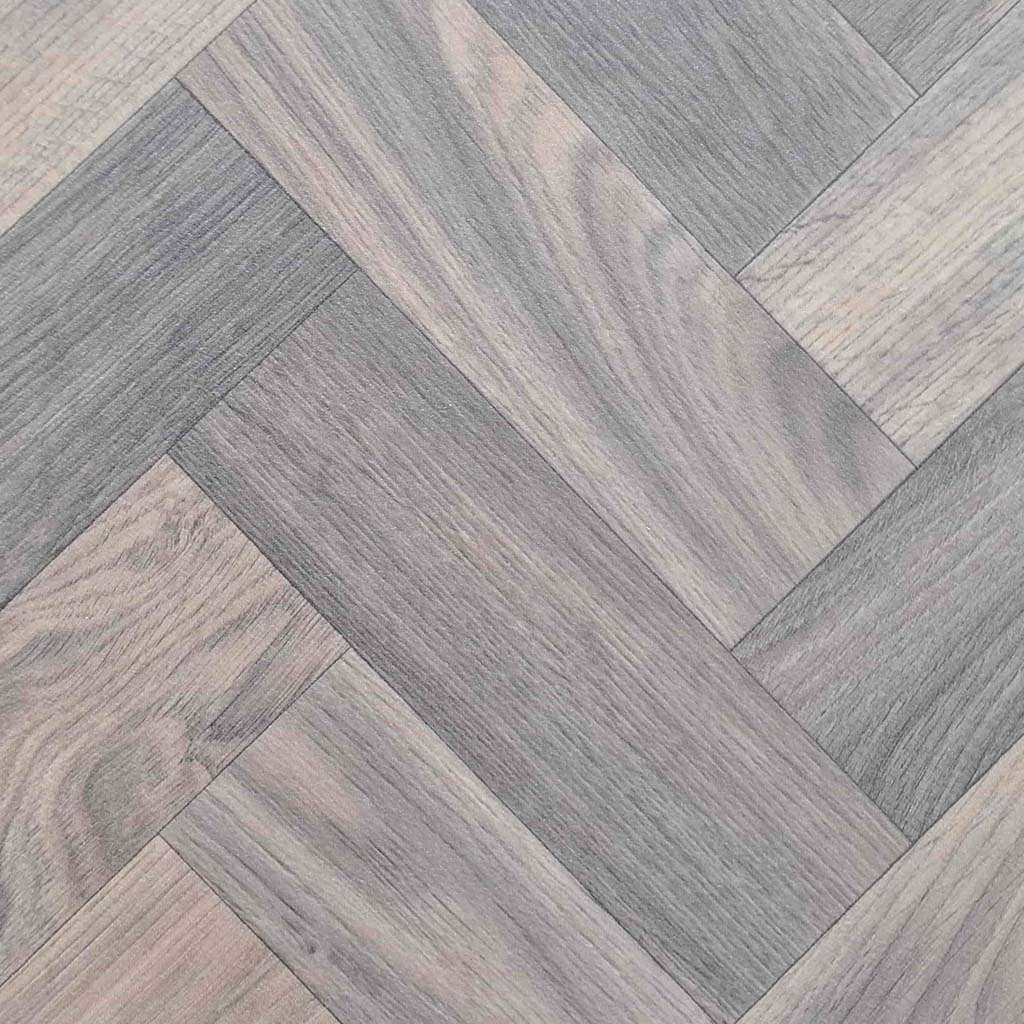 A close up of a wooden floor with a herringbone pattern.