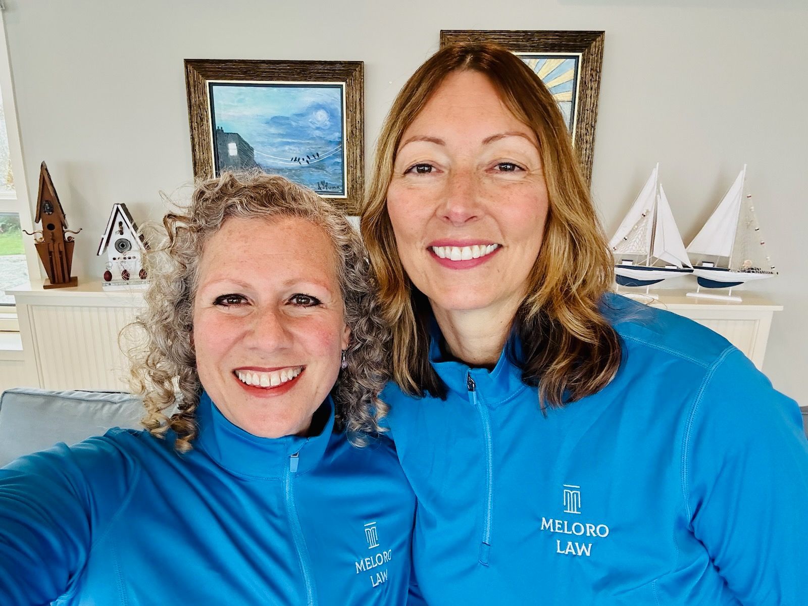 Two women wearing blue jackets are posing for a picture.