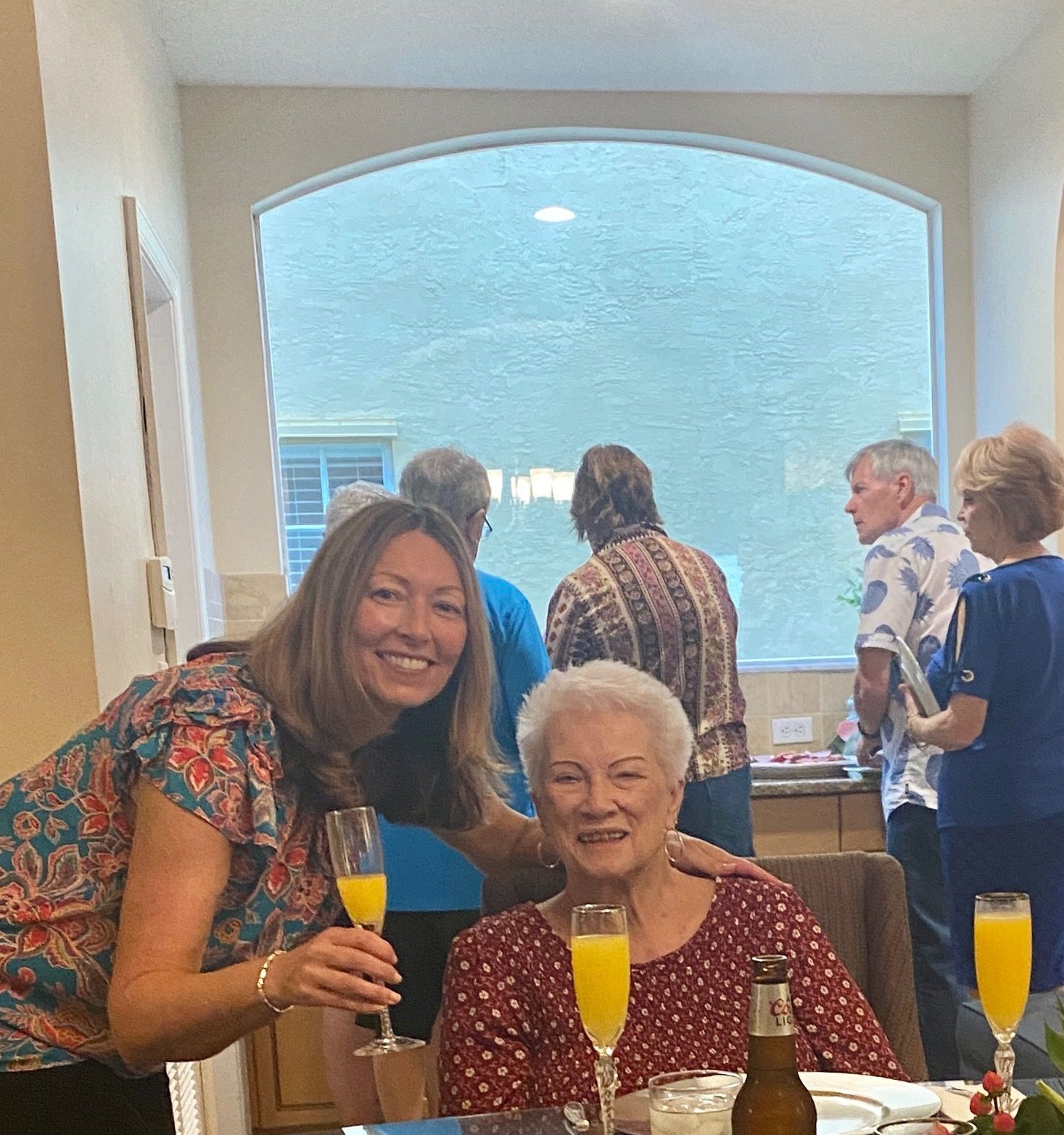Two women are posing for a picture while sitting at a table with champagne glasses.
