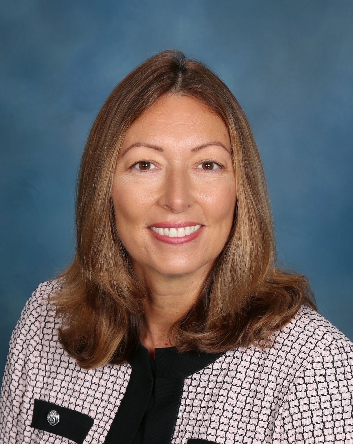 A woman in a pink and black jacket is smiling for the camera.