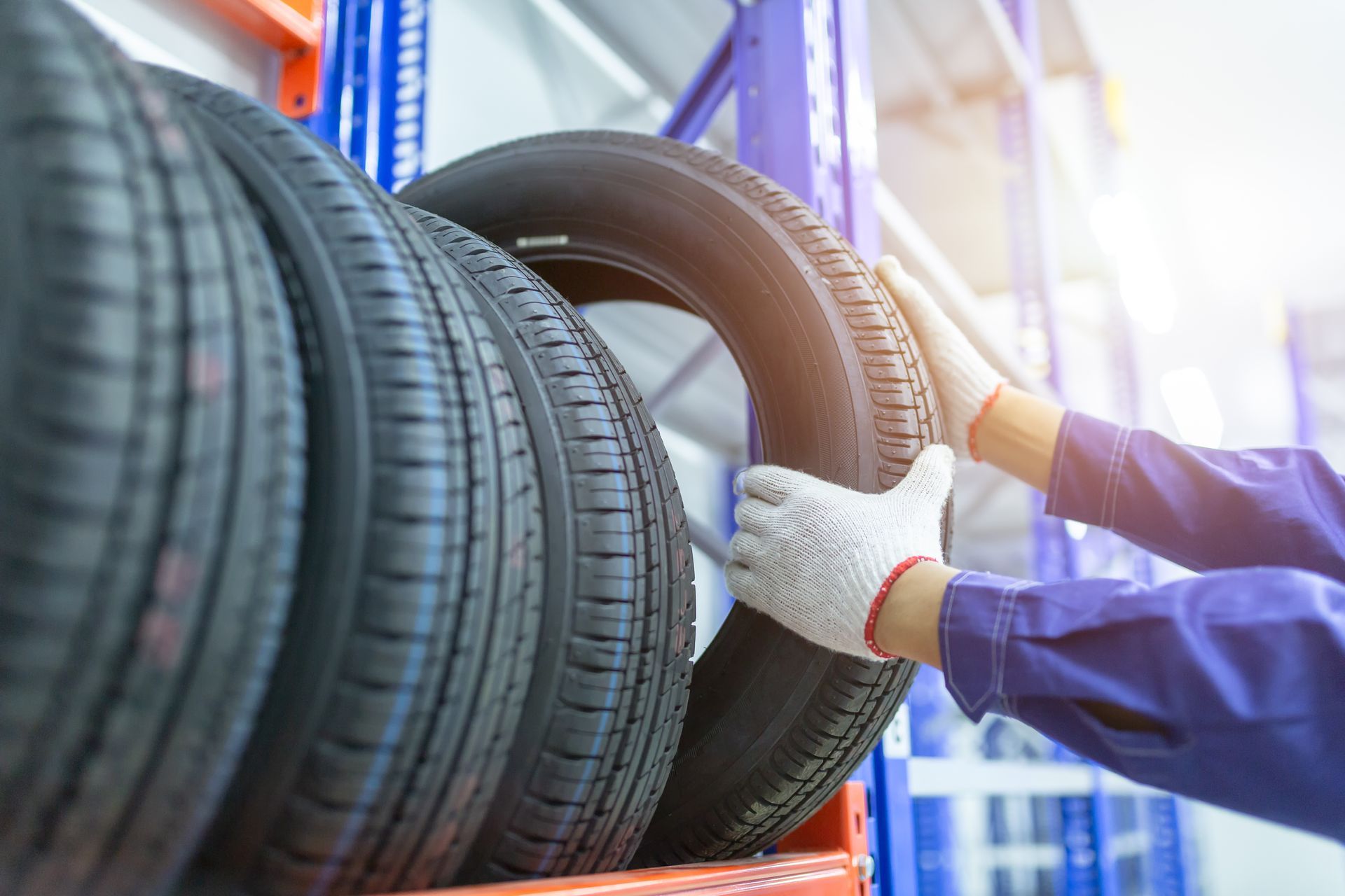 A person wearing white gloves and a blue uniform placing or removing a tire from a metal rack. A person wearing white gloves and a blue uniform placing or removing a tire from a metal rack.