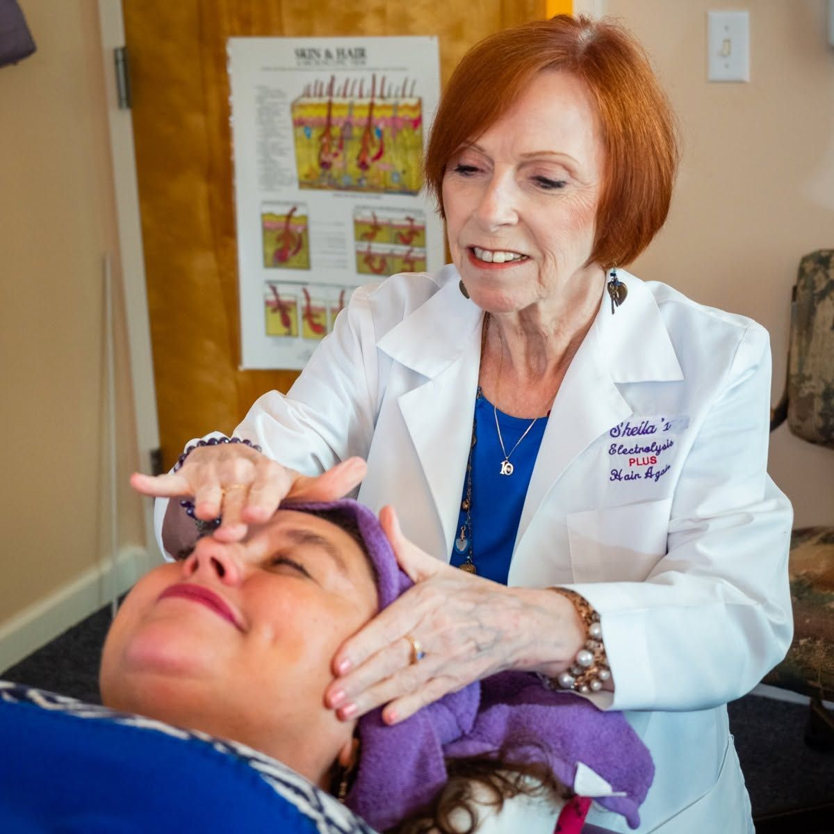 Doctor examining a patient’s face in a clinic, with anatomy poster in the background