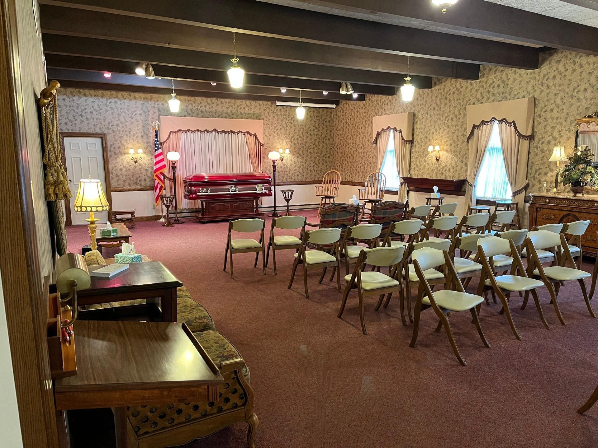 Funeral home interior with seating for a service. A casket sits in the front.