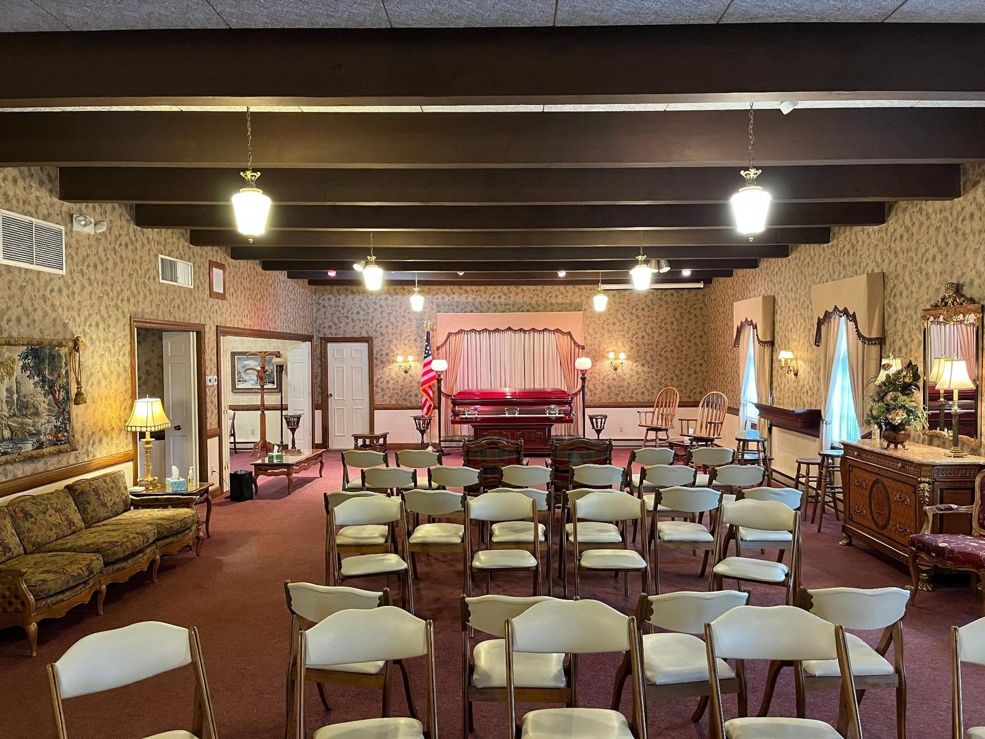 Funeral home interior, rows of chairs face a draped altar, with a casket.