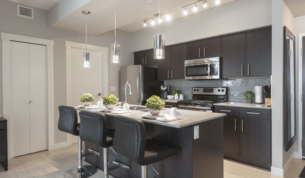 Modern kitchen with dark cabinets, stainless steel appliances, and an island with bar seating.