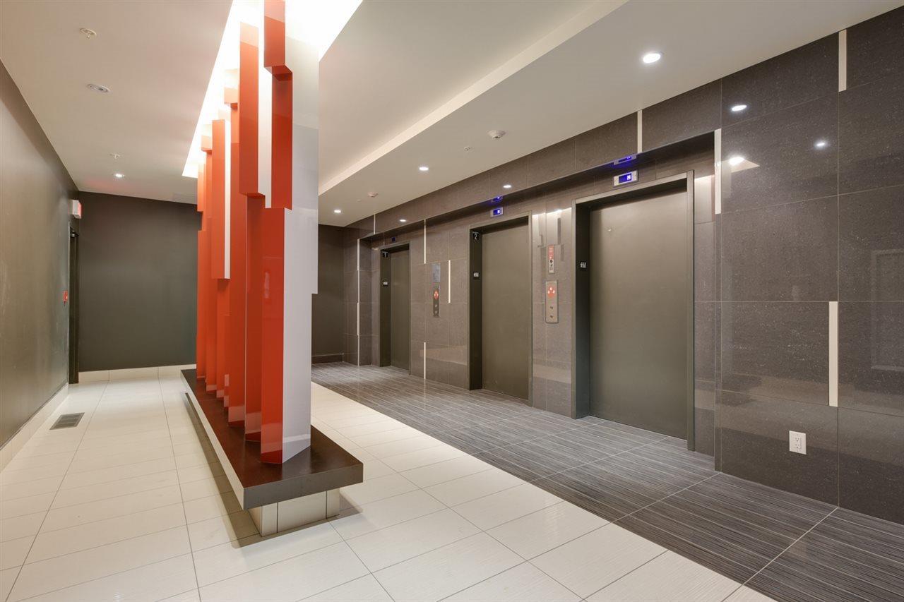 Hallway with elevators; red and white accents, gray walls and flooring, and three elevator doors.