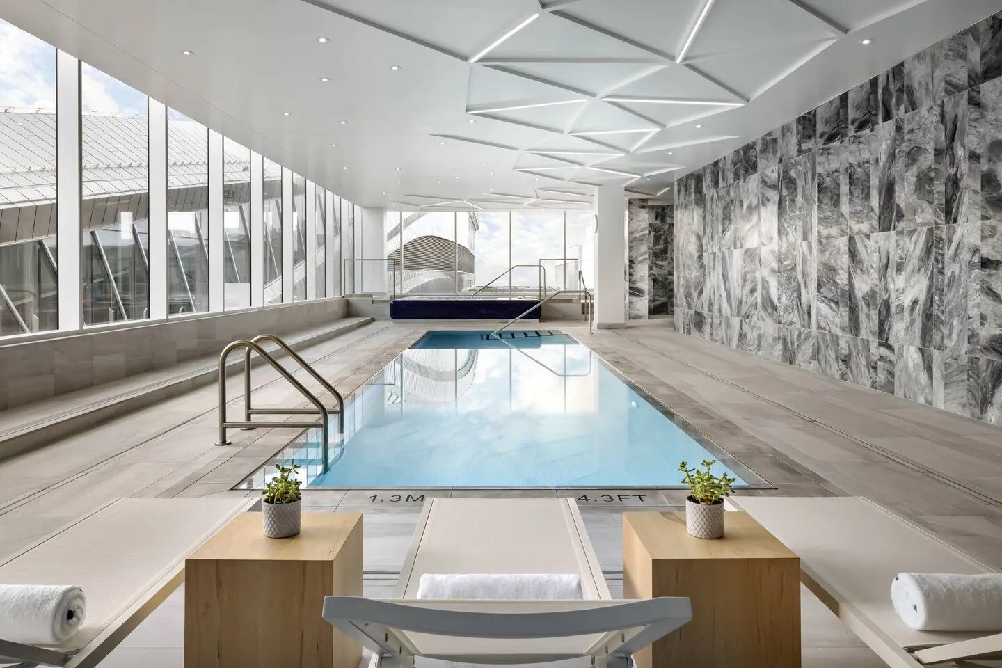 Indoor pool with lounge chairs, city views, and artistic wall.