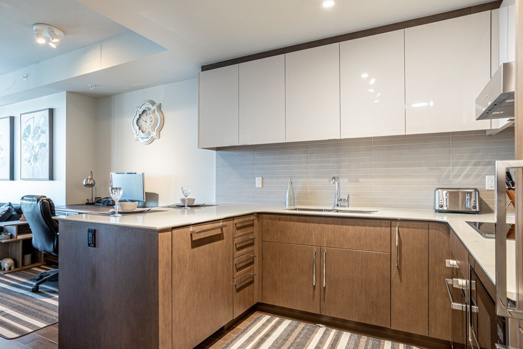 Modern kitchen with light and dark wood cabinets, a countertop and a small striped rug.