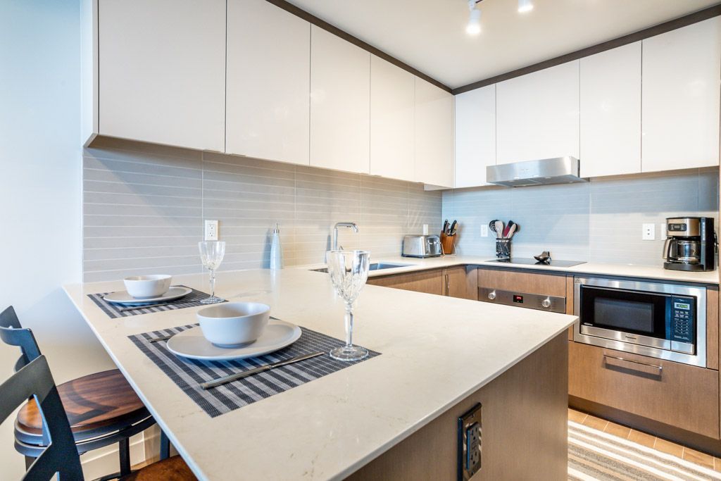 Modern kitchen with white cabinets, wooden island, and dining setup for two.