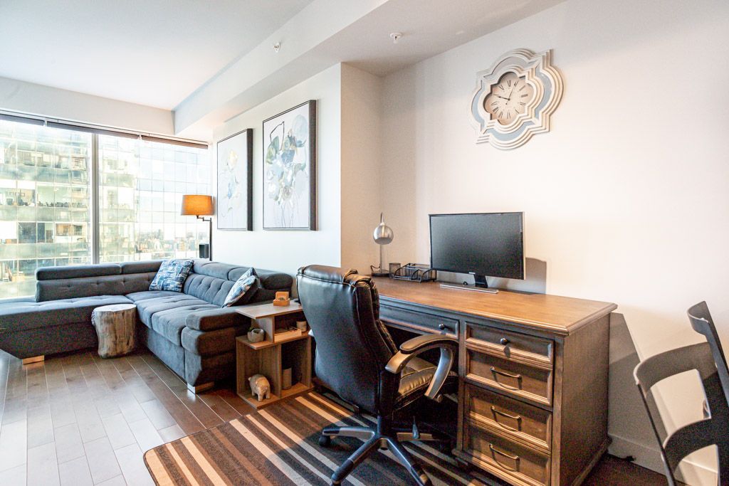 Living room with desk, sofa, and artwork; hardwood floors.