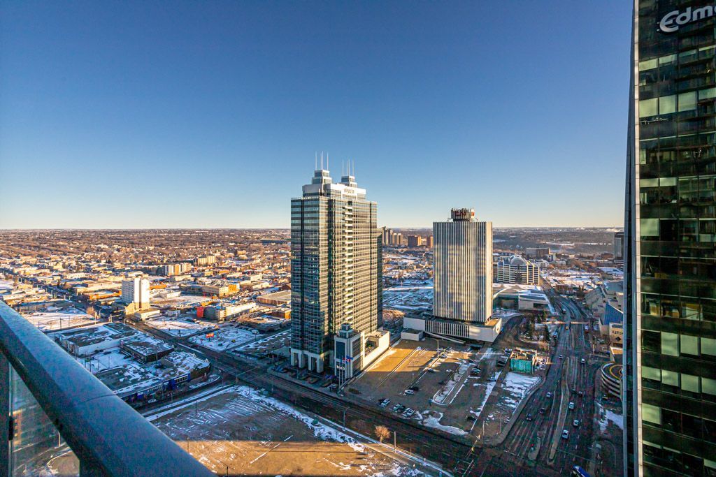 High-angle view of cityscape with skyscrapers, roads, and snowy patches under a clear, blue sky.