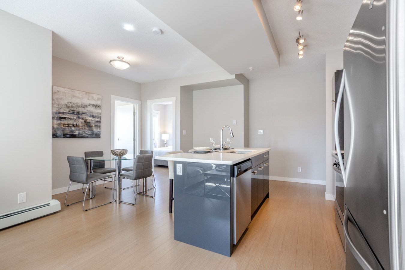 Modern kitchen and dining area with gray walls, stainless steel appliances, and island.