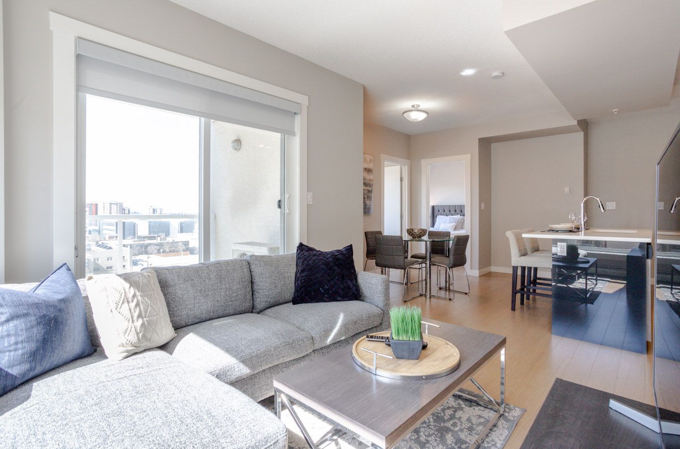 A modern living room with a grey sectional, coffee table, and dining area.