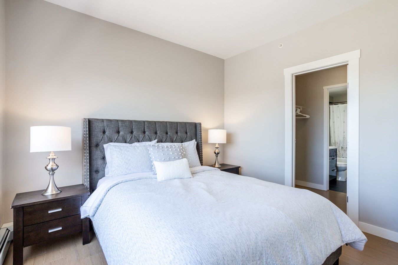 A bedroom with a bed, bedside tables, and a doorway to a bathroom.