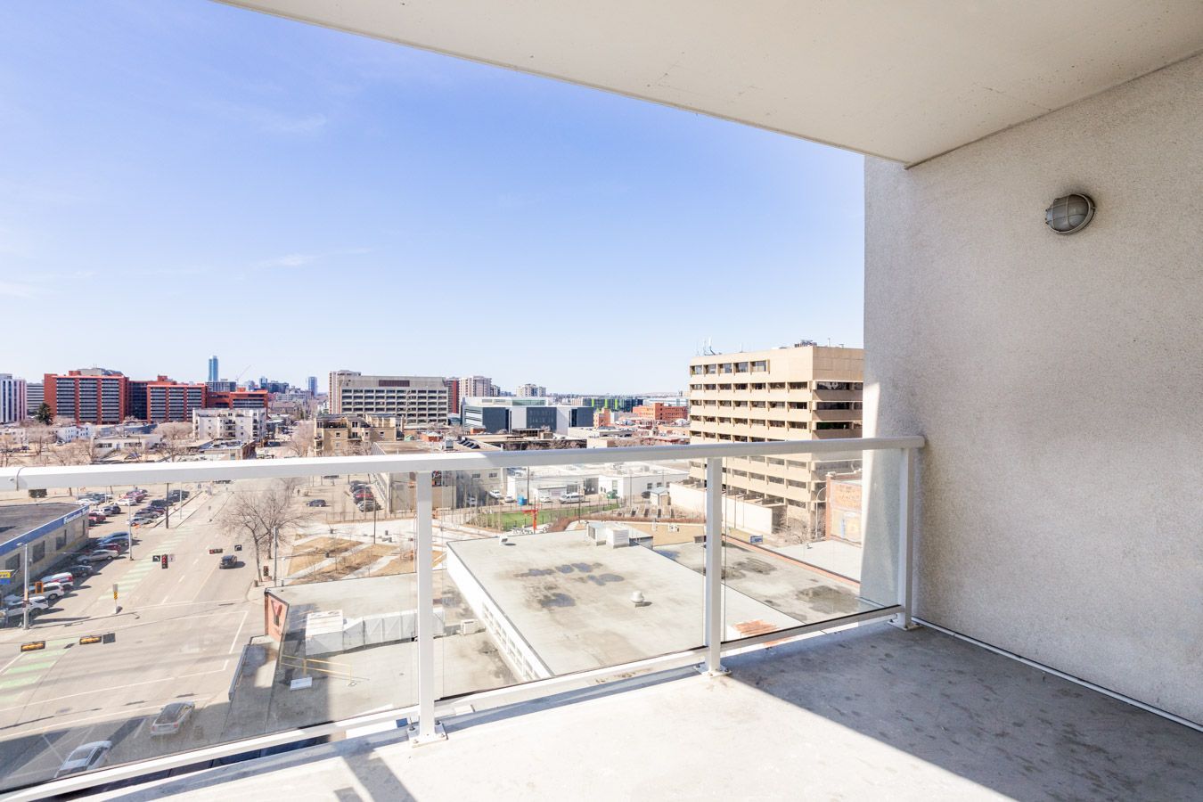 Balcony view of cityscape with glass railing, bright blue sky, and construction site.