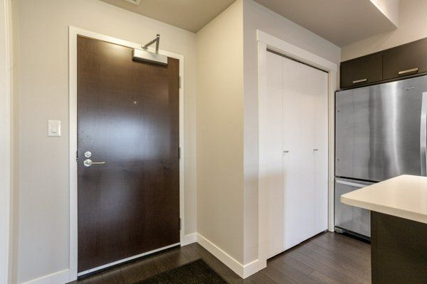 Entryway with dark brown door, white closet, and stainless steel refrigerator.