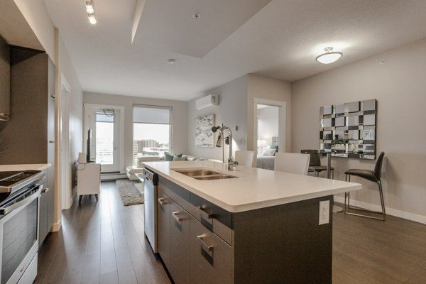 Modern open-concept kitchen and living area with an island, dining table, and access to a balcony.