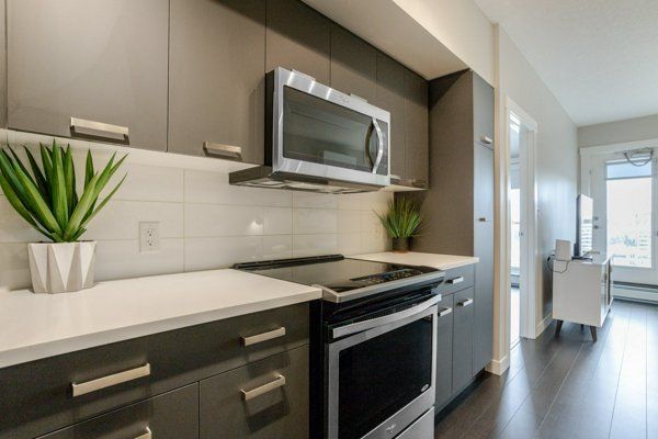 Modern kitchen with gray cabinets, white countertops, and stainless steel appliances.