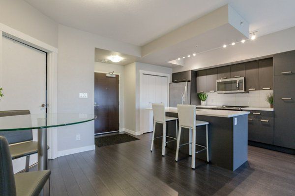 Modern kitchen with dark cabinets, island with stools, and dining table.