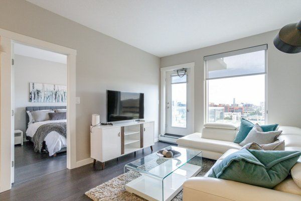 Living room with white sofa, TV, and open doorway to bedroom.