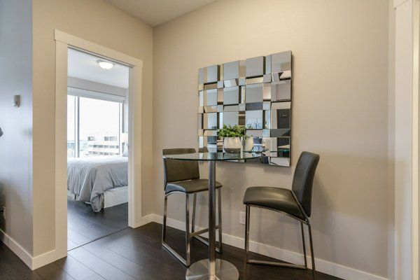 A small dining nook with a table, chairs, and a decorative mirror next to a bedroom doorway.