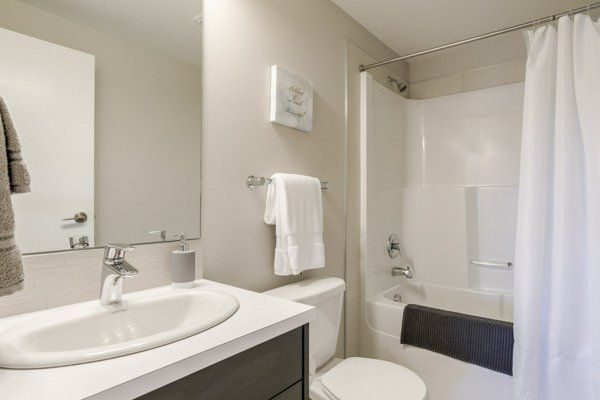 A bathroom with a sink, toilet, tub, and a towel rack. Neutral tones with white and gray.