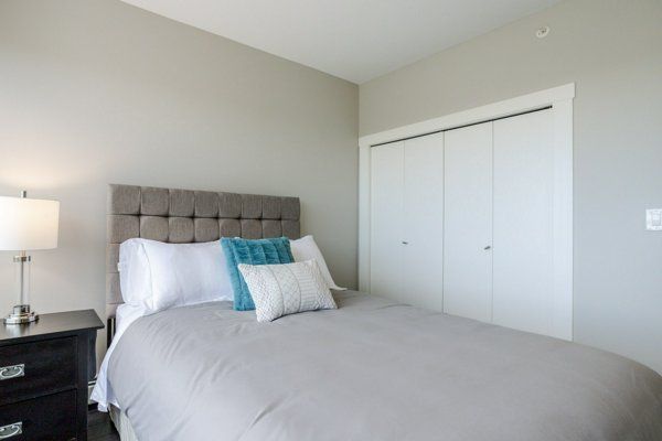 Bedroom with grey bedding, a black nightstand, and a white closet.