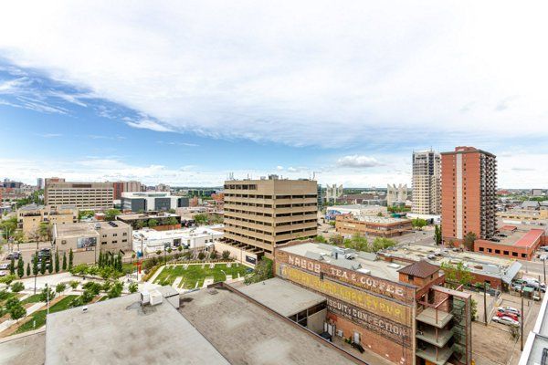 City skyline with buildings under a cloudy blue sky; some brown, red, and tan buildings.
