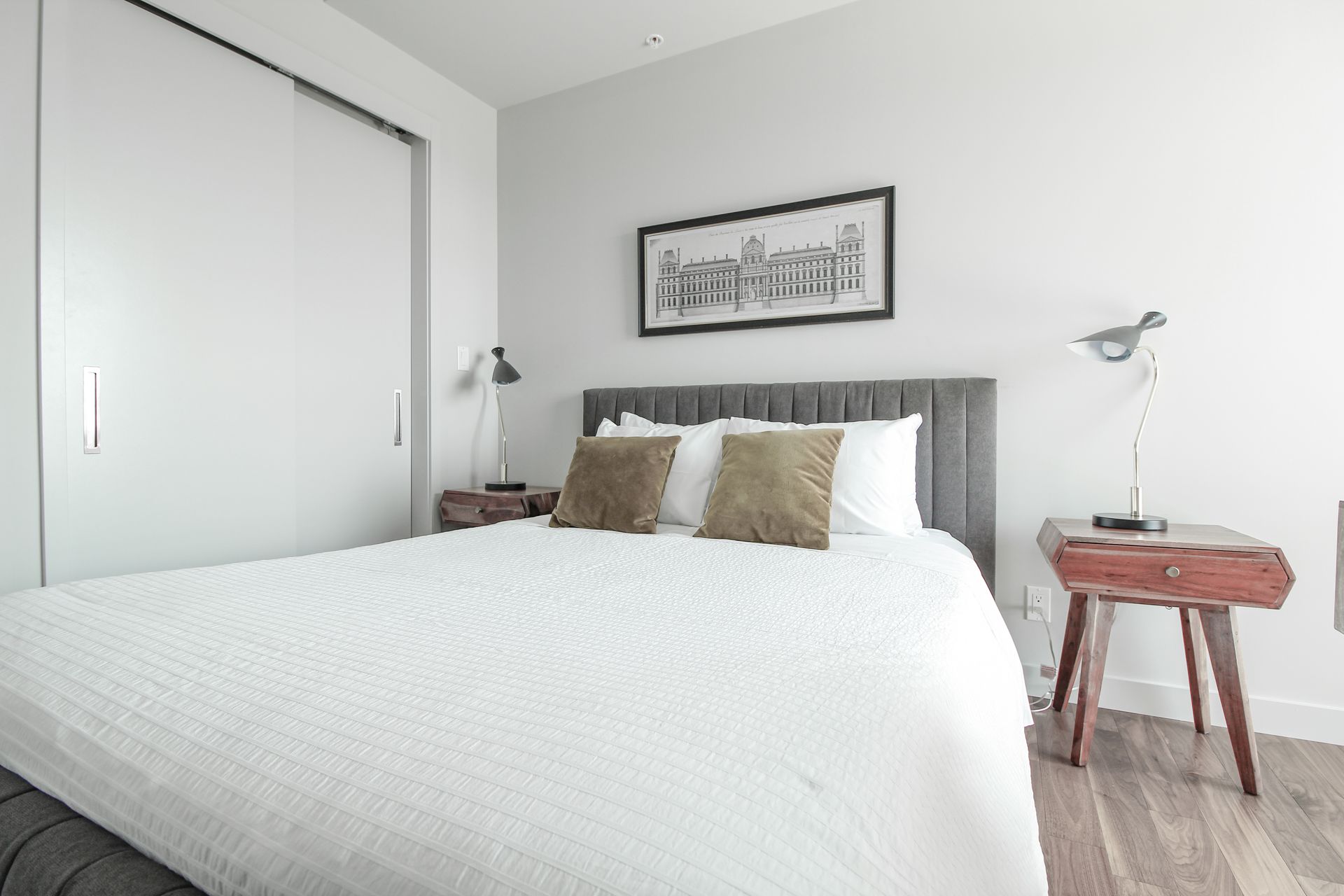 Bedroom with a bed, two nightstands with lamps, and art on the wall.