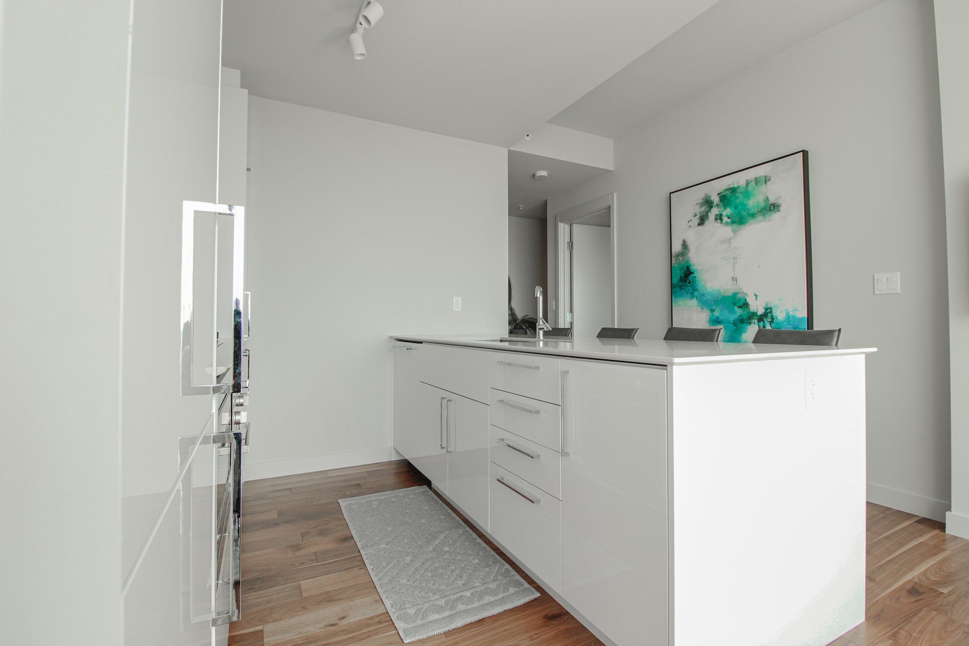 White spacious kitchen area with modern white cabinets and hardwood flooring