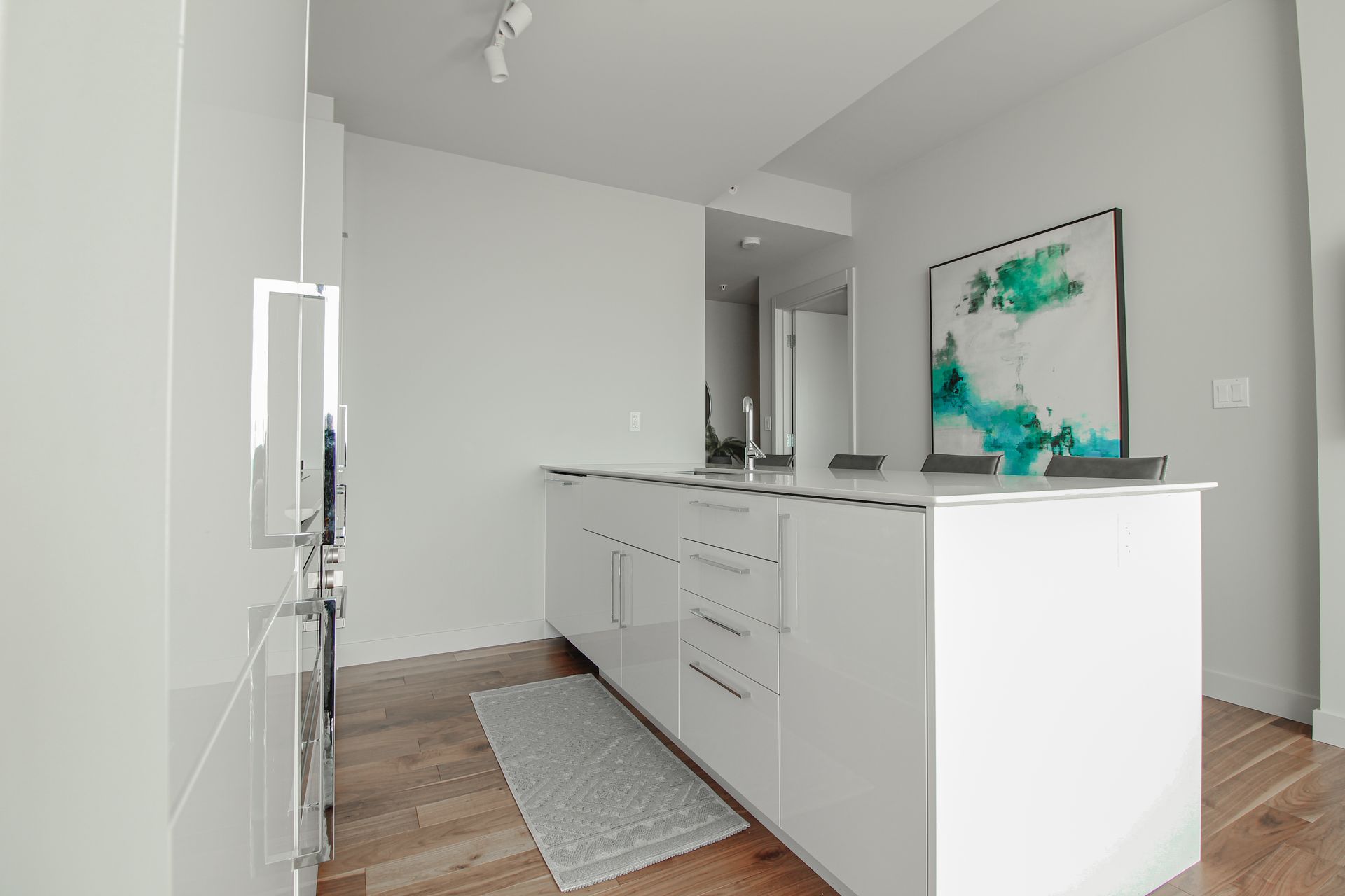 Modern white kitchen island with art, wood floors.