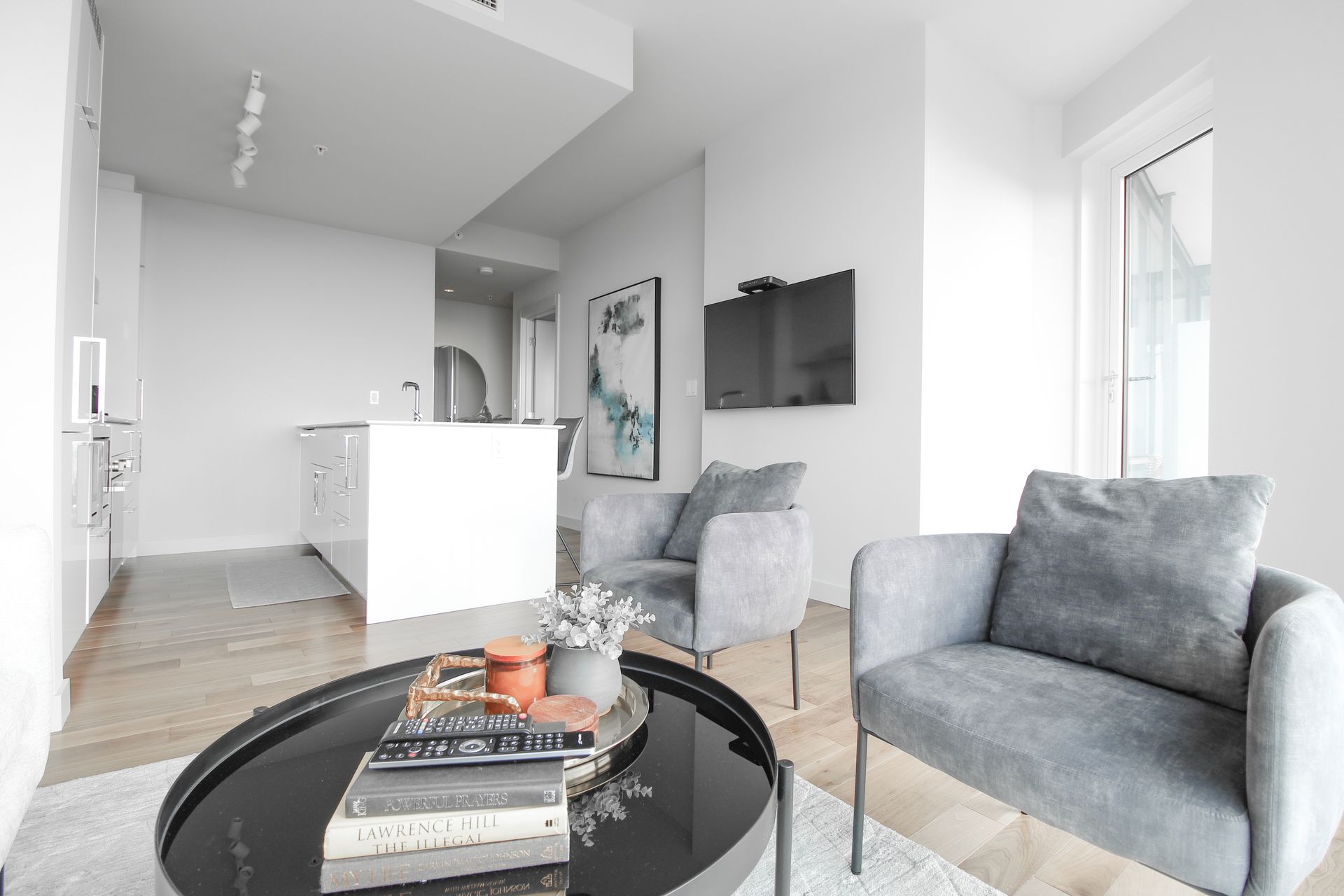 Modern living room with gray armchairs, coffee table, and artwork.